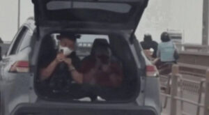 Một chiếc xe ôtô đang chở hai người ngồi trong khoang hành lý