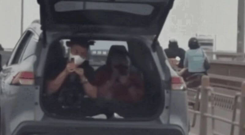 Một chiếc xe ôtô đang chở hai người ngồi trong khoang hành lý