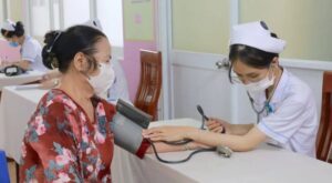 Nhân viên y tế đang đo huyết áp cho người tới khám bệnh