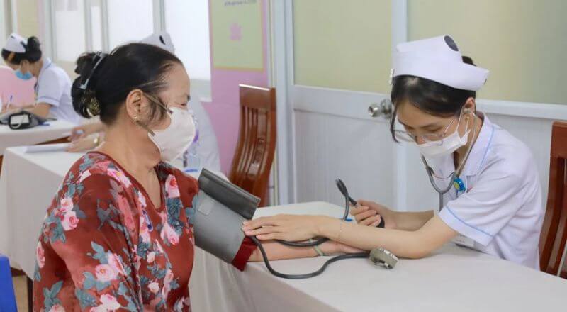 Nhân viên y tế đang đo huyết áp cho người tới khám bệnh